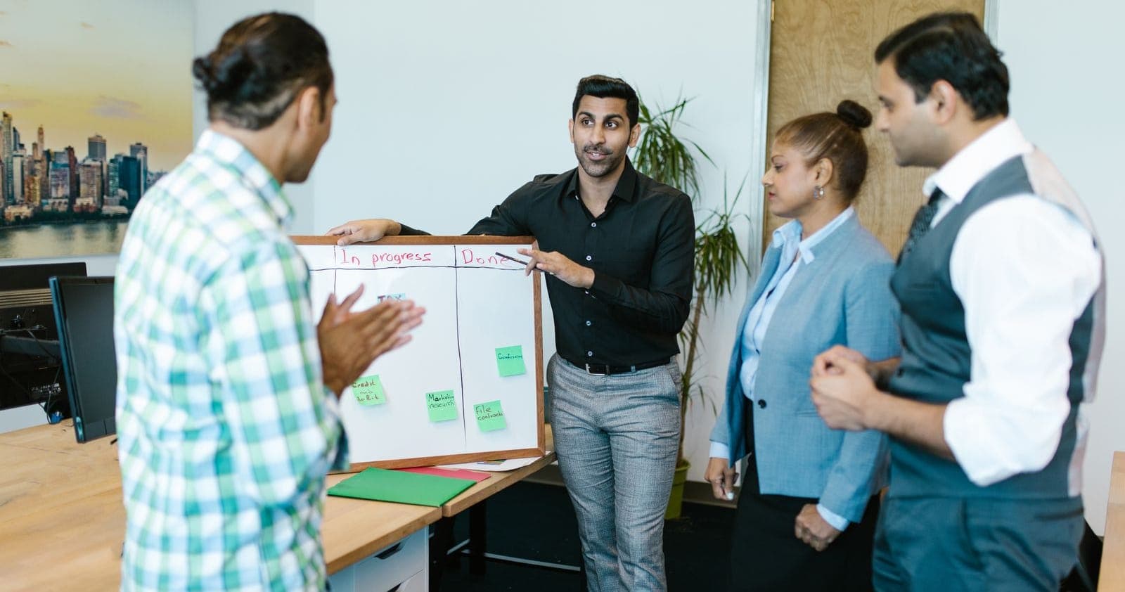 An Indian web development team reviewing project phases on an In progress and Done task board in an office