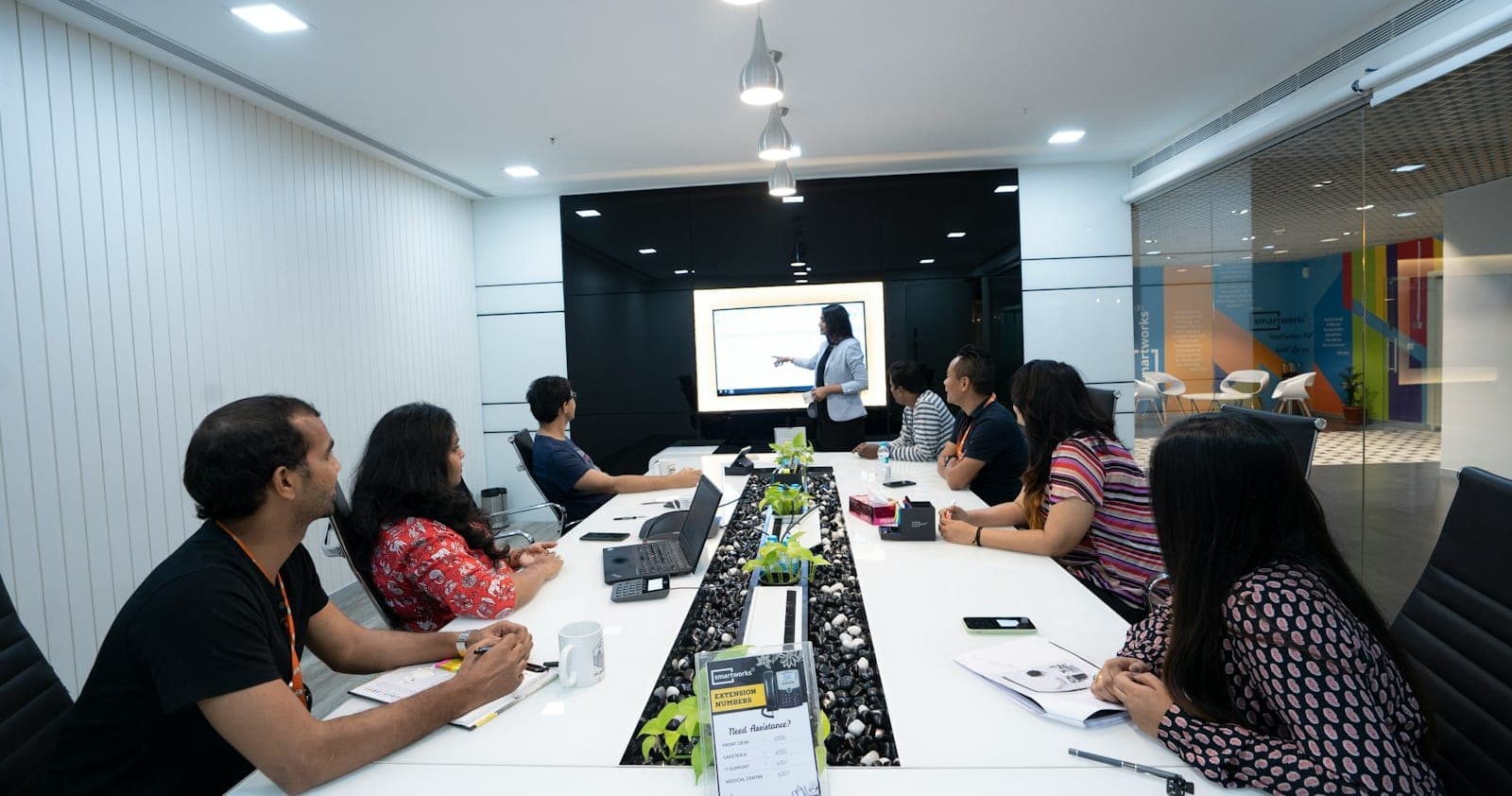 An Indian product team reviewing a presentation on screen in a glass-walled meeting room in New Delhi